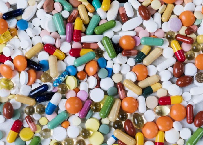 Vibrant assortment of medicine capsules and tablets in a flatlay format, highlighting diversity in pharmaceuticals.